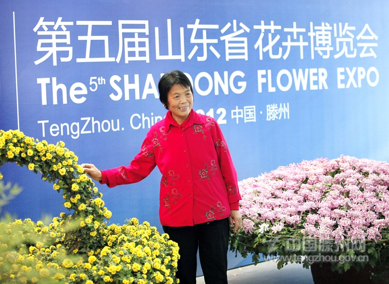 第五屆山東省花卉博覽會(huì)展覽館內(nèi)，一位市民正在展牌前留影